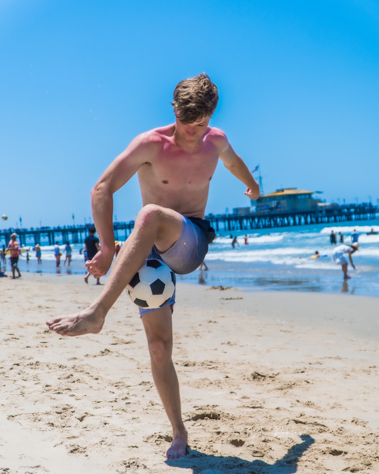 Soccer kick on the sand by the pier